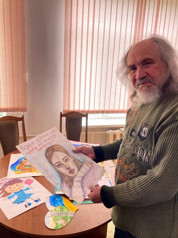 Просвітництво в дії: народний художник України Валерій Франчук і діти. Франчук з картиною в руках. Франчук розглядає дитячі малюнки